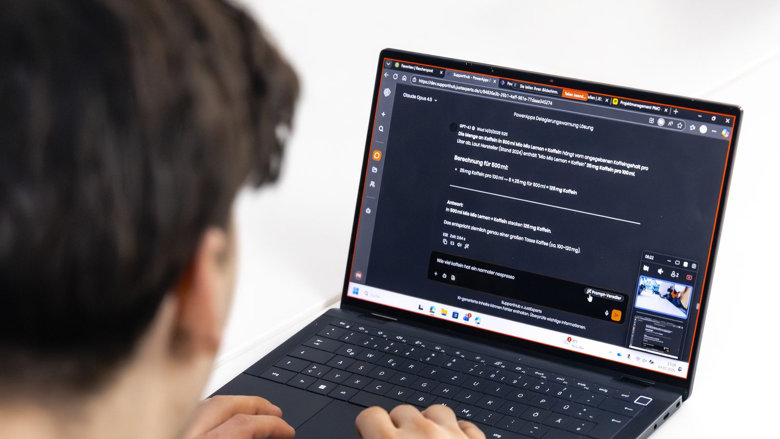 Blick über die Schulter auf einen Laptop mit einem KI-Chat