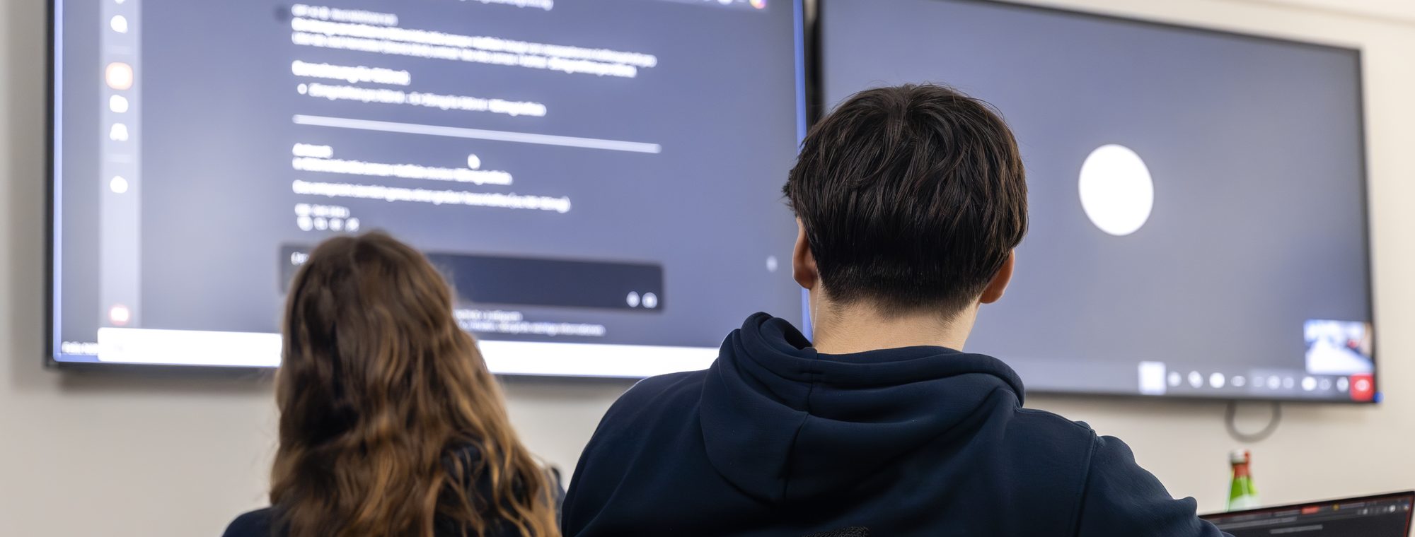 Zwei Kolleg:innen von just experts arbeiten gemeinsam an einem Bildschirm